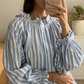 Light blue stripe cotton blouse with soft ruffles at the neck and wrists. 